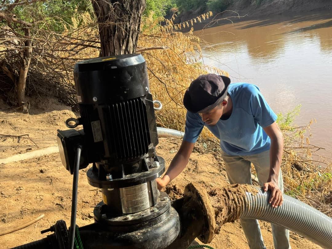 DAMAL team member checking an irrigation pump by the river